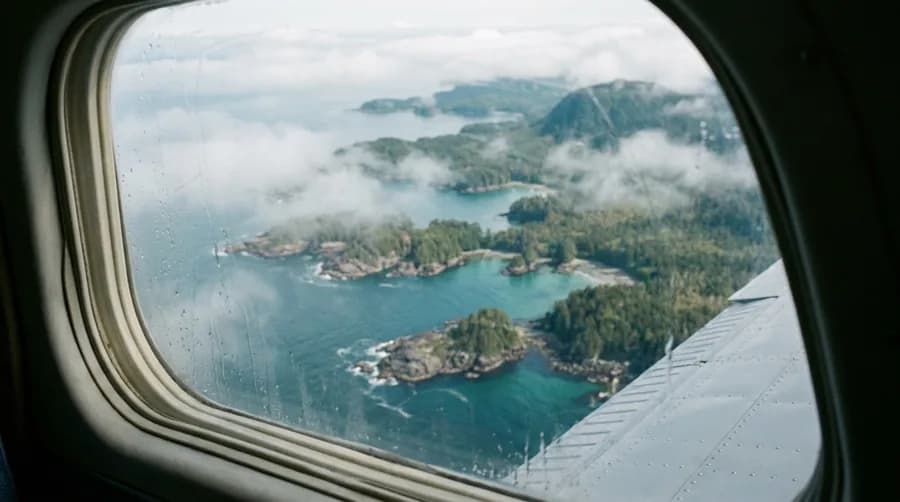 Blick aus einem Flugzeugfenster auf eine Küste mit kleinen Buchten und Inseln