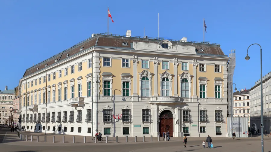 Das Bundeskanzleramt am Ballhausplatz in Wien bei blauem Himmel, mit österreichischer Fahne auf dem Dach