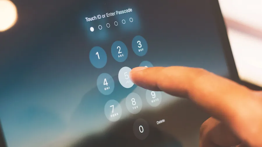 Finger tippt auf dem Bildschirm eines Tablets einen Zahlencode in das Ziffernfeld der Sperre ein