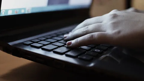 Eine Hand liegt auf der Tastatur eines aufgeklappten Laptops