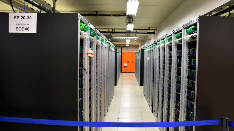 Gang zwischen zwei Reihen schwarzer Serverschränke im Rechenzentrum des CERN, vorne ein blaues Absperrband
