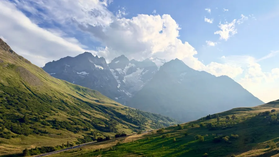 Beispielfoto aus der Hauptkamera des iPhone 18 Pro: grüne Almwiese mit einer Straße vor Bergen mit Gletscherresten unter Wolken