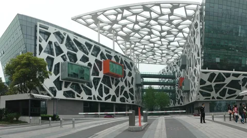 Die Firmenzentrale von Alibaba in Hangzhou, ein weiter Vorplatz vor einem Gebäude mit wabenförmiger weißer Fassade